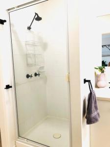La salle de bains est pourvue d'une douche avec une porte en verre. dans l'établissement Trinity Beach Sea Breeze 3 Bedroom Apartment, à Trinity Beach