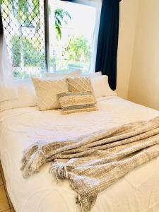 - un lit avec une couverture, des oreillers et une fenêtre dans l'établissement Trinity Beach Sea Breeze 3 Bedroom Apartment, à Trinity Beach