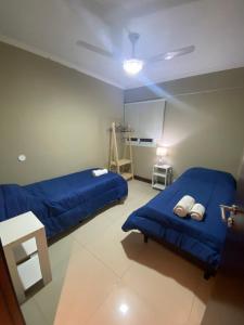 2 camas en una habitación con sábanas azules y una mesa en Departamento Alsina al mil en Salta