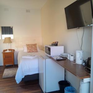 a small room with a bed and a desk with a microwave at The Frontier Motel in Dorrigo
