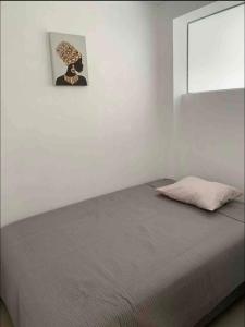 a bed in a white room with a picture on the wall at Departamento en centro histórico en 4to piso in Ayacucho