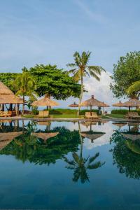 a pool at a resort with chairs and umbrellas at Jimbaran Puri, A Belmond Hotel, Bali in Jimbaran