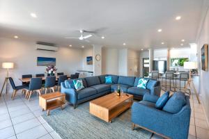 a living room with blue couches and a dining room at Blue Water Views 16 - 3 Bedroom Penthouse with Ocean Views in Hamilton Island