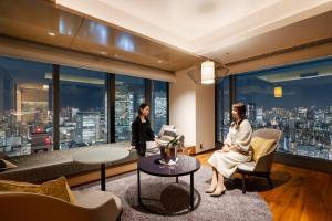 two women in a living room with a view of a city at THE BLOSSOM HIBIYA in Tokyo