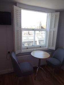 a room with a table and two chairs and a window at Aquarium Guest House in Brighton & Hove