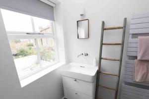 a white bathroom with a sink and a window at Stylish Georgian townhouse on Richmond Hill in Richmond