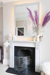 a living room with a fireplace with a mirror at Stylish Georgian townhouse on Richmond Hill in Richmond