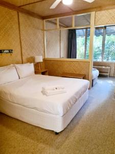 Tallow Beach Motel في خليج بايرون: غرفة نوم مع سرير أبيض كبير في غرفة