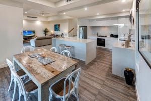 a kitchen and living room with a wooden table and chairs at La Bella Waters 5 Oceanview Private Garden BBQ Buggy in Hamilton Island