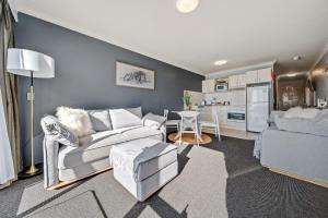 a living room with a couch and a table and a kitchen at Horizons 306 - Deluxe Lake Front Studio l Pool l Tennis l WiFi l BBQ in Jindabyne +18 photos