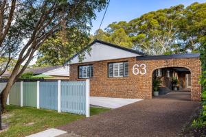 a brick house with a white fence in front of it at Little Beach Boutique Apartment Pet Friendly in Nelson Bay