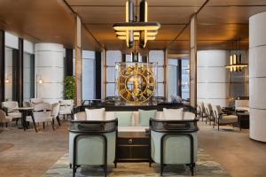 a lobby with a large clock and tables and chairs at Swissotel Beijing Hong Kong Macau Center in Beijing