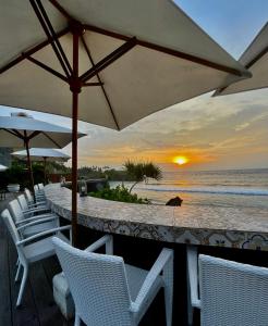 een strandbar met witte stoelen en een parasol bij The Palms Ceningan Hotel in Nusa Lembongan
