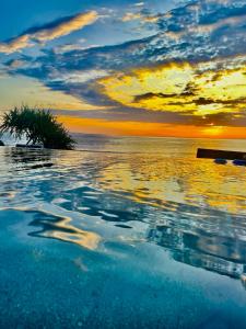 a swimming pool with a sunset in the water at The Palms Ceningan Hotel in Nusa Lembongan
