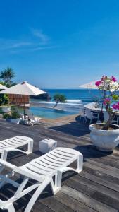 een houten terras met witte stoelen en een zwembad bij The Palms Ceningan Hotel in Nusa Lembongan