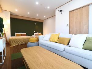a living room with a couch and two beds at Hotel & Glamping ACT FUTTSU in Futtsu