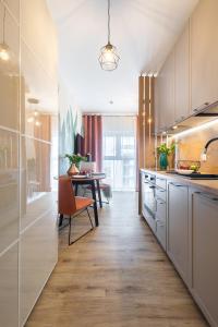 a kitchen with white cabinets and a dining table at Apartamenty Jaworska 4 Wrocław in Wrocław