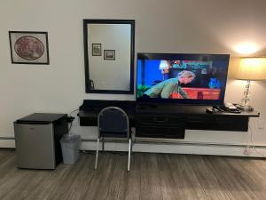 a living room with a flat screen tv on a dresser at Central Motel in Fort Morgan