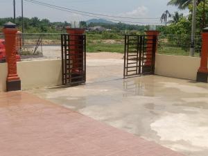 un patio con dos puertas abiertas y una valla en Adilah Homestay B en Pasir Puteh