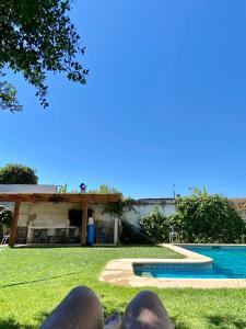 une personne assise dans l'herbe à côté d'une piscine dans l'établissement Alojamientos San Sebastián Talca, à Talca