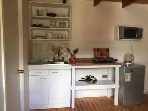 a kitchen with white cabinets and a sink and a refrigerator at Linda y cómoda casa interior entera/independiente in San Pedro de la Paz