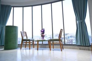 Hotel The Faam في راجكوت: طاولة وكراسي في غرفة بها نوافذ
