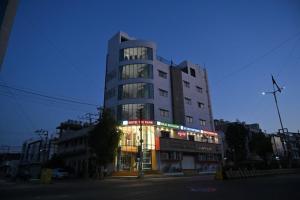 a tall building with lights in front of it at Hotel The Faam in Rajkot