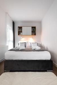 a white bedroom with a large bed with two pillows at Apartamenty Jaworska 4 Wrocław in Wrocław