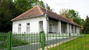 a white house behind a green fence at Van egy ház in Erdőhorváti
