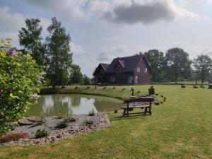 une maison avec un étang et un banc dans une cour dans l'établissement Stay at Svaja, à Plungė