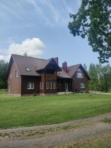 a large brown house with a large grass yard at Stay at Svaja in Plungė