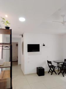 a living room with a table and a tv on a wall at Hotel Pousada Santa Maria in Aparecida