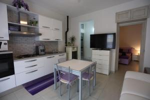 a kitchen with white cabinets and a table with chairs at La casa di Anna in Fluminimaggiore