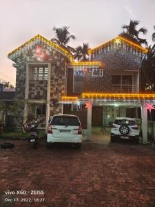 a house with two cars parked in front of it at His Grace Holiday Home - Nr to Malpe Beach in Udupi
