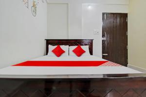 a bedroom with a large bed with red pillows at Flagship Gokul Residency in Bangalore