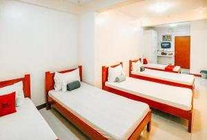 Cette chambre comprend 3 lits blancs et rouges. dans l'établissement RedDoorz S&L Apartelle Daraga Albay, à Legazpi
