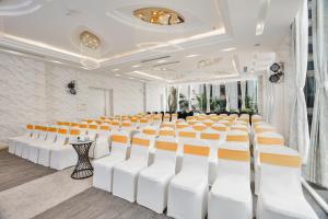 Cicilia Hotels & Spa Danang Powered by ASTON في دا نانغ: قاعة المؤتمرات مع الكراسي البيضاء والبرتقالية