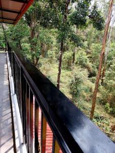 a balcony of a house with a view of a forest at ROYAL GRAND Homestay & Resort in Vālpārai