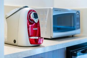 a red mixer sitting on a counter next to a microwave at Bay Motel Safety Beach in Safety Beach