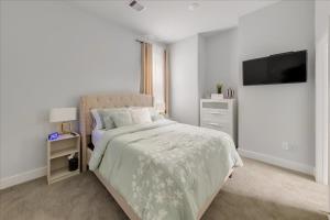 a white bedroom with a bed and a flat screen tv at Azaliah Luxe Connection in Houston