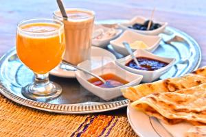 a table with a plate of food and a drink at Hotel-Restaurant Le Kaouki in Sidi Kaouki