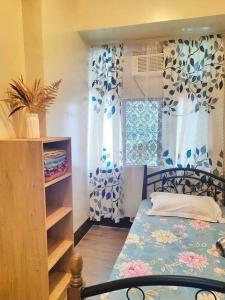 1 dormitorio con 1 cama y una ventana con cortinas en Spacious 3BR Condo Unit with Wi-Fi and pool access in San Juan near Greenhills, en Manila
