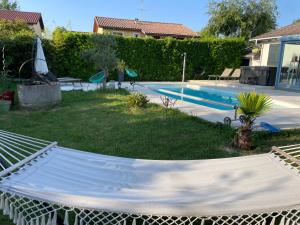 a hammock in a yard next to a swimming pool at Villa poétique proche de Lyon in Saint-Marcel-en-Dombes