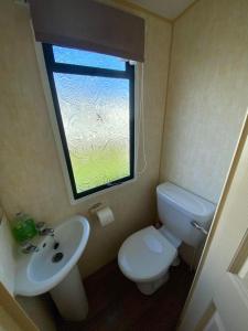 a bathroom with a toilet and a sink and a window at The Grange - Ingoldmells - Fantasy Island in Ingoldmells