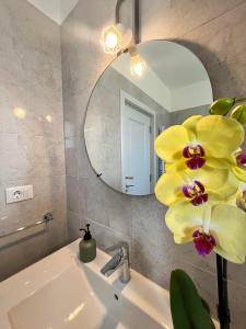 baño con lavabo con espejo y flor amarilla en Dio's Apartment 29F-1 en Sfîntu Ilie