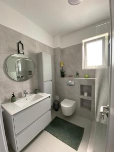y baño con lavabo, aseo y espejo. en Dio's Apartment 29F-1 en Sfîntu Ilie