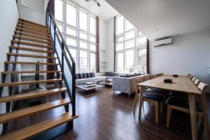 sala de estar con escalera, mesa y sofá en The BEEHIVE KAMIFURANO, en Kami-furano