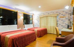 a hotel room with two beds and a chair at Wen Sha Bao Motel-Xinying in Xinying