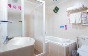 a bathroom with a tub and a sink and a shower at Wen Sha Bao Motel-Xinying in Xinying