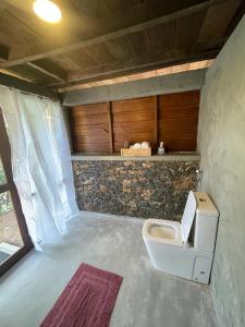 a bathroom with a toilet and a stone wall at Watersmeet Glamping in Deraniyagala +33 photos